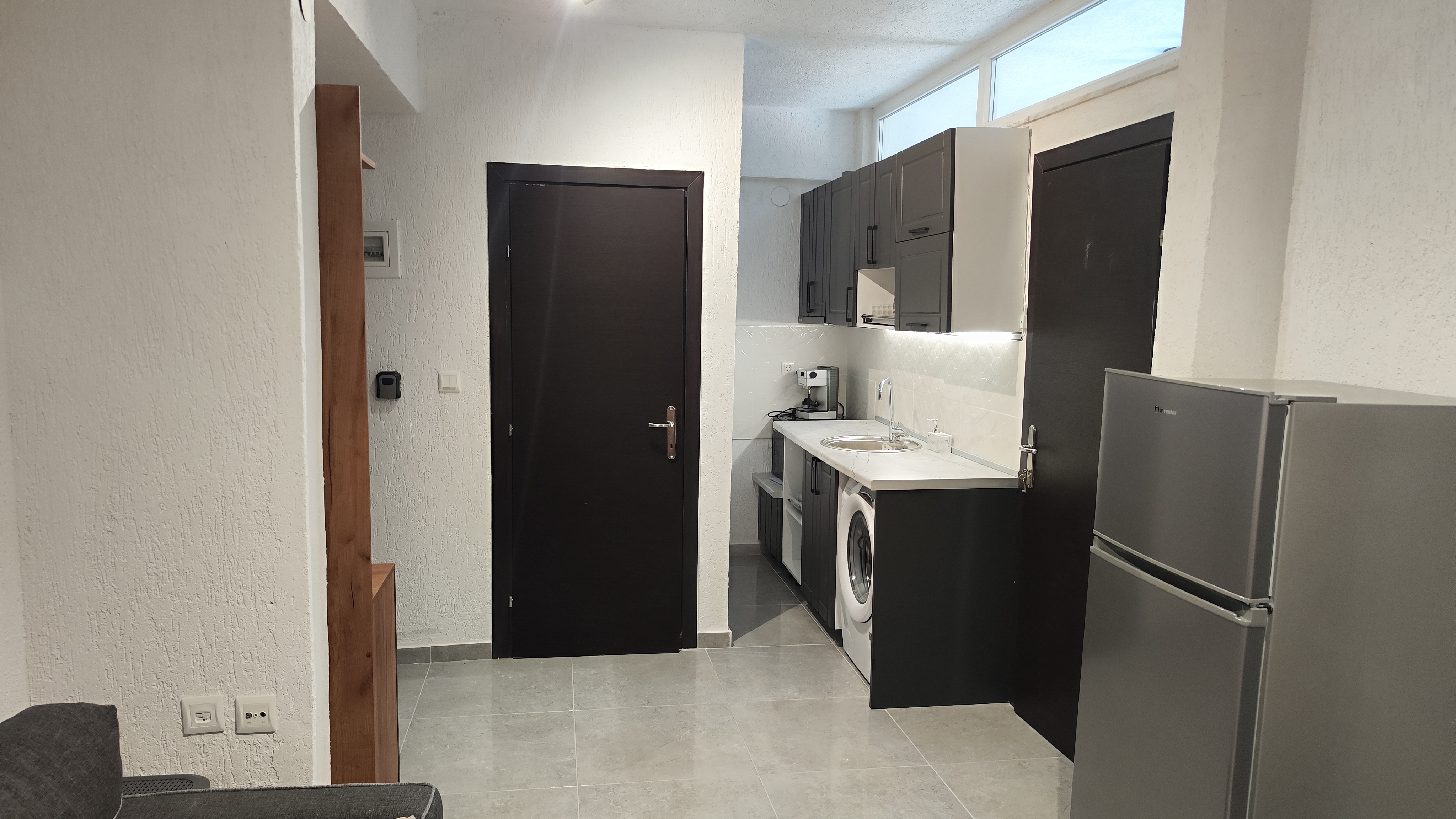 Kitchen counter with sink, hob, kettle and coffee machine against a tiled splashback